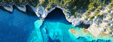 Aerial Drone Ultra Wide Photo Of Tropical White Rocky Bay Of Blue Lagoon With Turquoise Clear Waters, White Volcanic Caves And Sail Boats Docked, Island Of Paxos, Ionian, Greece