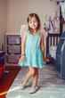 Cute adorable pretty dressed preschool girl playing a fairy princess at home. Child creativity imagination and fantasy dreams concept. Beautiful Caucasian kid in blue dress pretending a fairy or elf.
