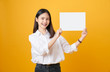 © sitthiphong - Young Asian woman holding blank paper with smiling face and looking on the yellow background. for advertising signs.