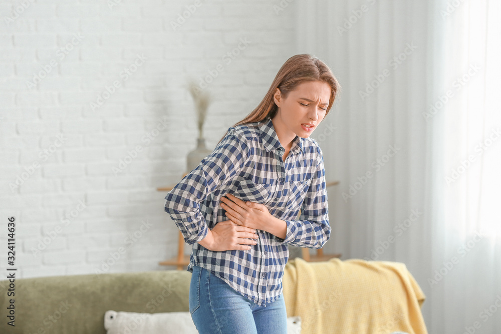 Young woman suffering from abdominal pain at home