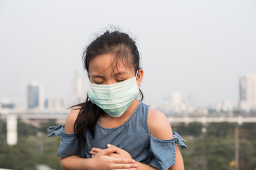 asian little child girl wearing a protection mask against PM 2.5 air pollution. sick girl with medical mask.  little girl using face mask to protect their health from pollution smog