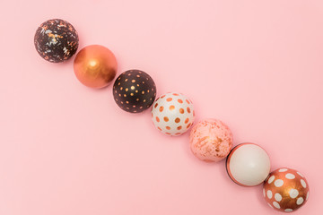 Wall Mural - Pink background with colorful easter eggs in a row painted in gold, white and black colors. Creative layout with copy space