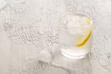 Glass of clear cold water with ice and lemon on white concrete background. Drinking water concept background