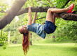 © Syda Productions - friendship, childhood, leisure and people concept - happy smiling little redhead girl hanging upside down on tree in summer park