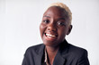 © Monkey Business - Portrait Of Smiling Young Businesswoman Wearing Suit Standing Against White Studio Wall