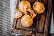 © Anikonaann - Fresh Traditional Australian meat mini pie on the wooden board on table background, closeup with copy space, rustic style