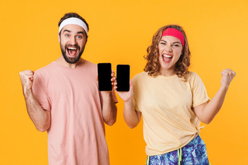 Poster - Portrait of athletic young couple smiling and using cellphones together