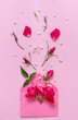 Spring composition with envelope and pink roses over pink background