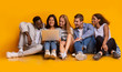 © Prostock-studio - Carefree teenagers sitting on floor and using laptop