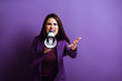 © LIGHTFIELD STUDIOS - irritated young woman screaming in megaphone while showing indignation gesture on purple background
