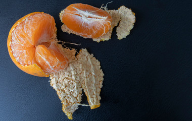 Top view, orange peeled by hand, placing orange on the floor. Healthy fresh orange. isolated on black. Healthy diet concept. Peeled oranges placed on black floor. Concept difference in same place