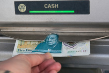 Person Withdrawing Money From UK United Kingdom Cash Machine ATM Withdrawal Hand Holding Five Pound Note. British Economy Visiting England British Tourism Concept Idea