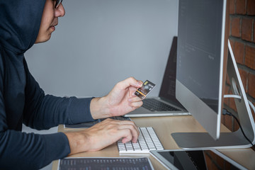 Wall Mural - computer hacker or cyber attack concept, dangerous hooded hacker using multiple computers typing bad