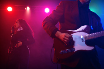 A jazz singer and guitarist perform on stage.