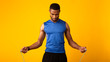 Handsome serious black guy exercising with skipping rope