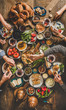 © sonyakamoz - Turkish breakfast. Flat-lay of peoples hands taking and eating Turkish pastries, vegetables, greens, cheeses, fried eggs, jams and tea in copper pot and tulip glasses over wooden background, top view