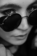 © Oleg Samoylov - Black-white close-up portrait of a beautiful young girl in black round sunglasses.Girl poses for the photographer.Fashion portrait