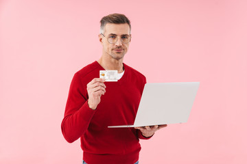 Wall Mural - Man isolated over pink wall holding credit card.