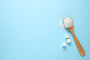 Sugar and spoon on light blue background, flat lay. Space for text