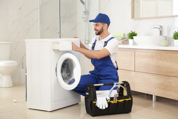 Canvas Print - Professional plumber repairing washing machine in bathroom