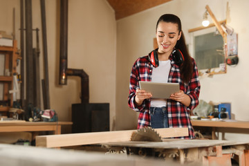 Professional carpenter with tablet near sawmill machine in workshop