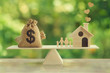 © Small Smiles_dimple - Property investment and house mortgage concept : Wooden home, Family member  and US dollar hessian bags on wooden balance scale. depicts family financial management for a residence.