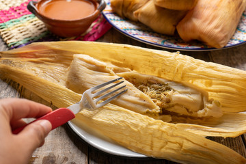 Mexican chicken tamales with green sauce on wooden background