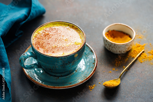 Closeup view of turmeric latte cup on a textured dark background. Tableau sur Toile