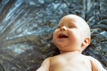 Giggling six month baby boy. Honest smile and laughter. Closeup, copy space, selective focus.