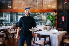 Portrait Of Smiling Man Serving A Dish In Restaurant
