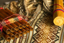 Close Up View Of Peruvian Pan Flute And Rain Stick On Traditional Colorful Textile. Concept Of Traditional Andean Music.