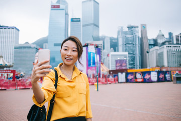 Wall Mural - Happy Asian woman taking selfie in city