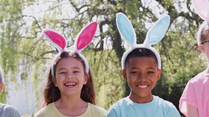 Wall Mural - Portrait Of Children Wearing Bunny Ears On Easter Egg Hunt In Garden