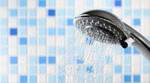 Shower Head With Flowing Water Stream In Blue Bathroom