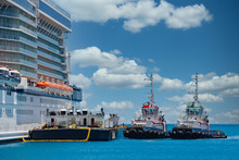 Two Tugboats And A Barge Tied Up To A Cruise Ship