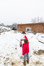 A Six Year Old Boy Building A Snowman