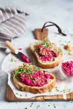 Bruschetta With Beetroot Hummus Decorated With Chopped Nuts And Microgreen. Vegan Recipes, Plant-based Dishes. Green Living Concept. Organic Food. Vegetarian Cuisine. Bread With Pink Dip