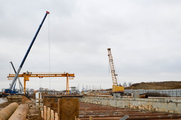 A construction site with specialized professional equipment and cranes during the construction of a modern line of the underground metro station in the big city of the metropolis