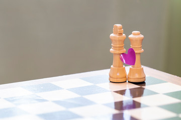 Love and marriage. Chess pieces on a chessboard with a heart symbol.