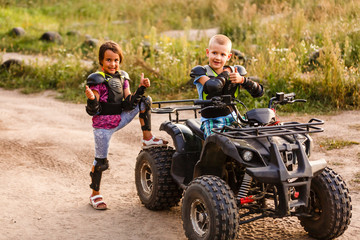 Wall Mural - Happy little children playing on road at the day time. They driving on quad bike in the park. Kids having fun on the nature. Concept of happiness.