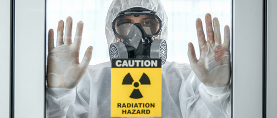 Wall Mural - scientist with coverall protection clothing and full face protection mask in control room with radiation hazard sign