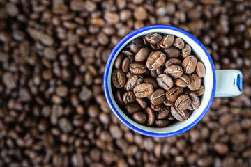 background. defocusing. Coffee beans in a white cup with a blue stripe. coffee beans on the table.