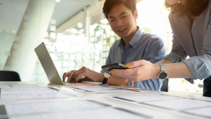 Wall Mural - cropped shot of ui developer working on laptop and document while consulting with co worker