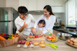 © ake1150 - Asian mother teaching her daughter shredded vegetable salad with father thumb up on the side while the family was cooking in the kitchen at home. Family life love relationship.