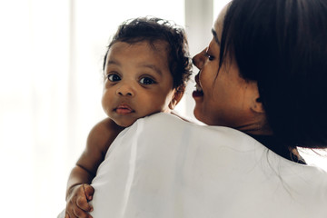 african american mother holding adorable little african american baby in her arms in bedroom.love of