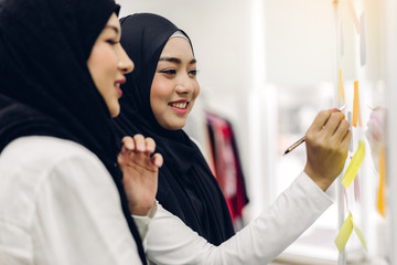 Wall Mural - Two muslim business woman planning and brainstorm writing over the project with stickers note on glass window at modern office.Teamwork concept