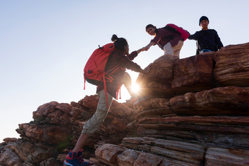 silhouette male and female hikers climbing up  mountain cliff .