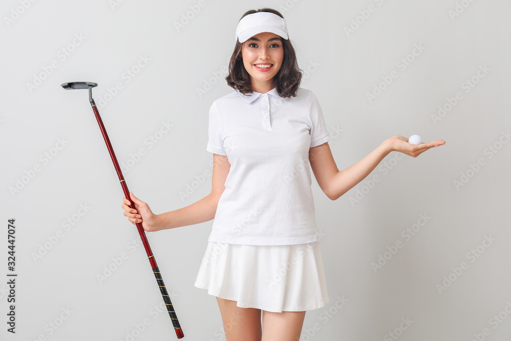 Beautiful female golfer on light background