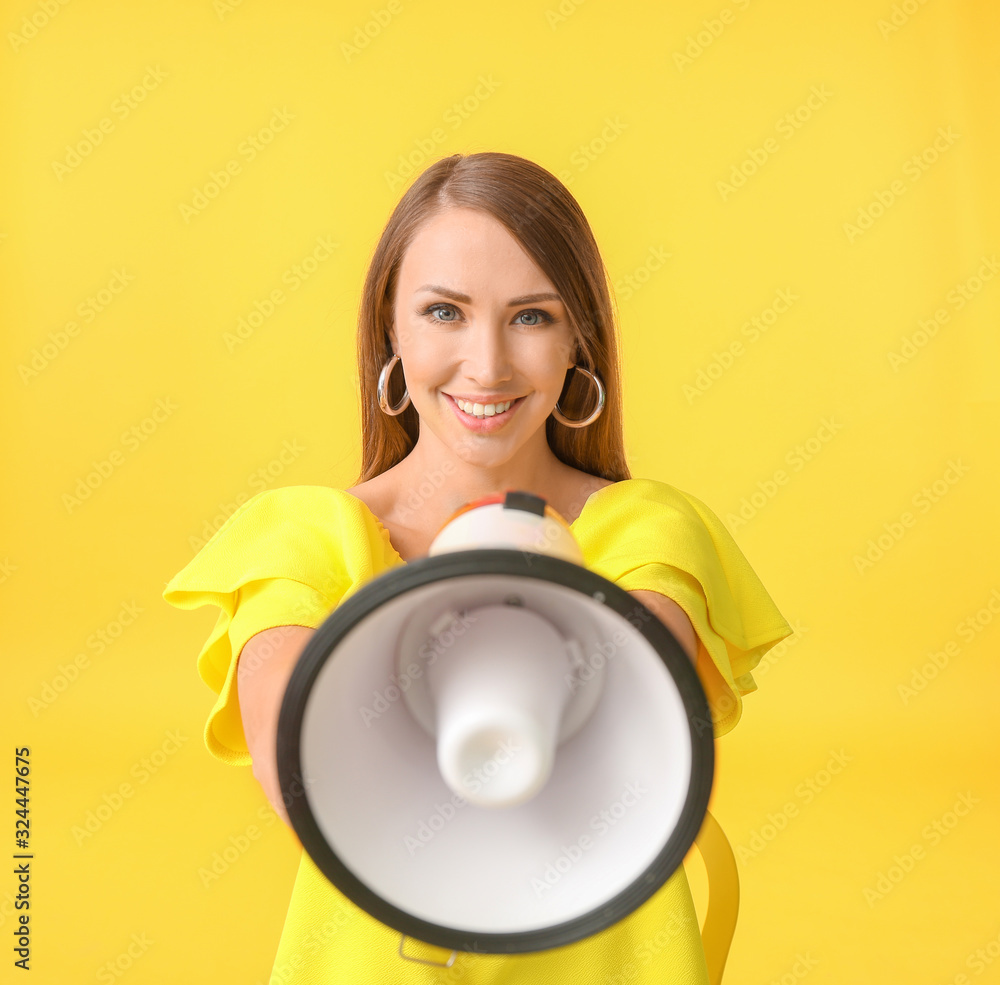 Young woman with megaphone on color background