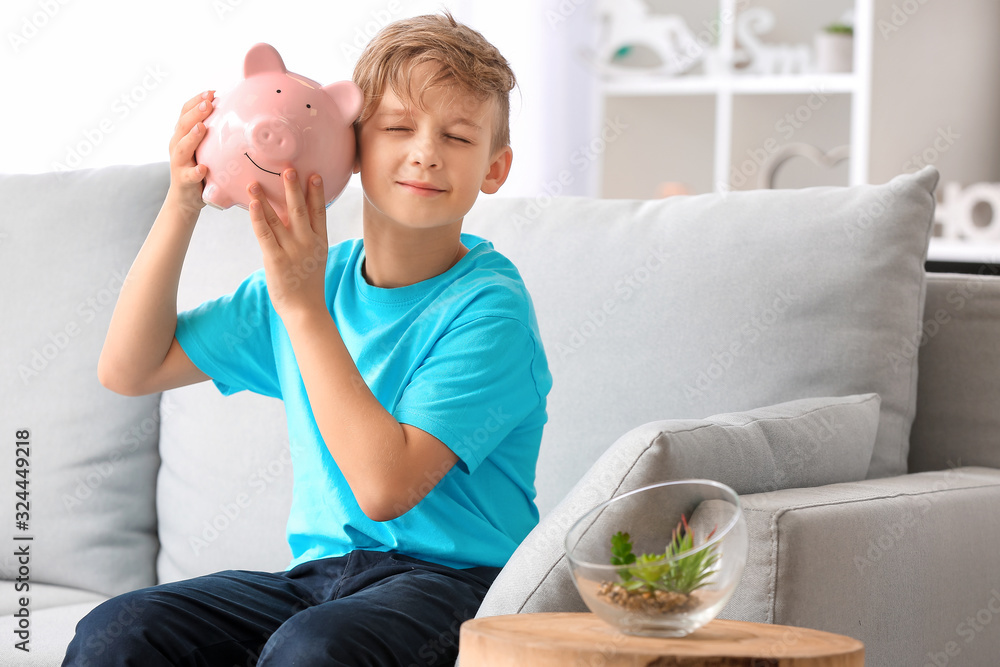 Cute boy with piggy bank at home